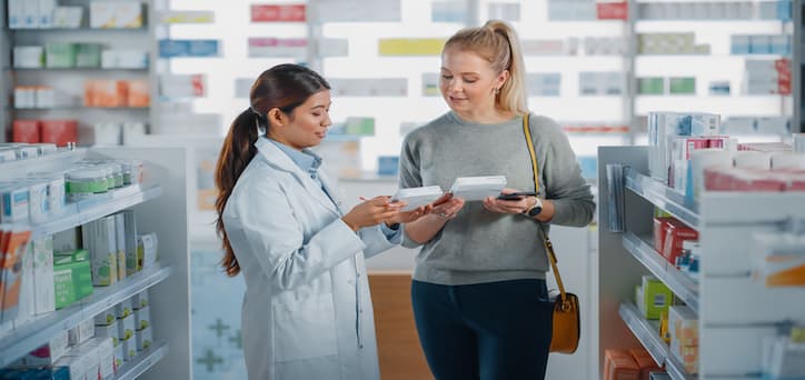 A woman showing the label of her prescription drug to the pharmacy technician