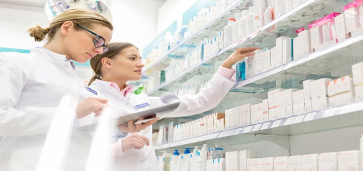 Female pharmacist holding a clipboard and a bottle of medication 